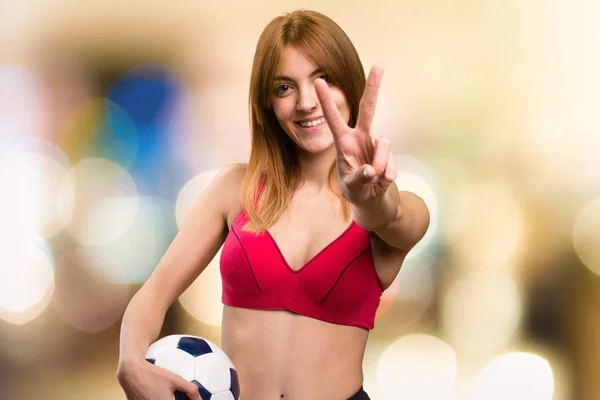 Jovem mulher esporte segurando uma bola de futebol em fundo desfocado — Fotografia de Stock
