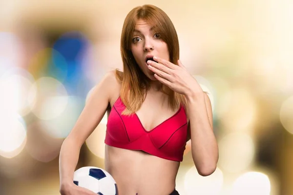 Молодая спортсменка держит футбольный мяч на неориентированном фоне — стоковое фото