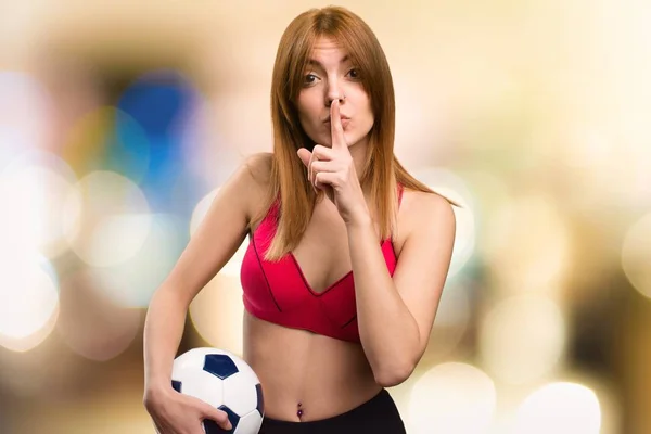 Νέος αθλητισμός γυναίκα που κρατά μια μπάλα ποδοσφαίρου σε αόριστες φόντο — Φωτογραφία Αρχείου