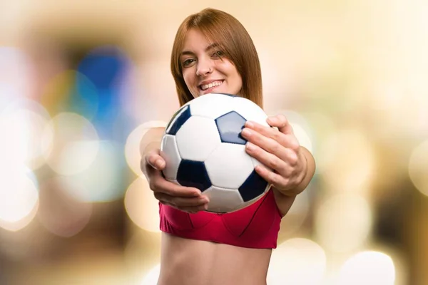 Giovane donna sportiva in possesso di un pallone da calcio su sfondo sfocato — Foto Stock