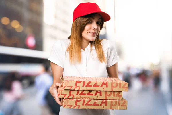 Pizza leverans kvinna gör oviktigt gest på ofokuserat ba — Stockfoto
