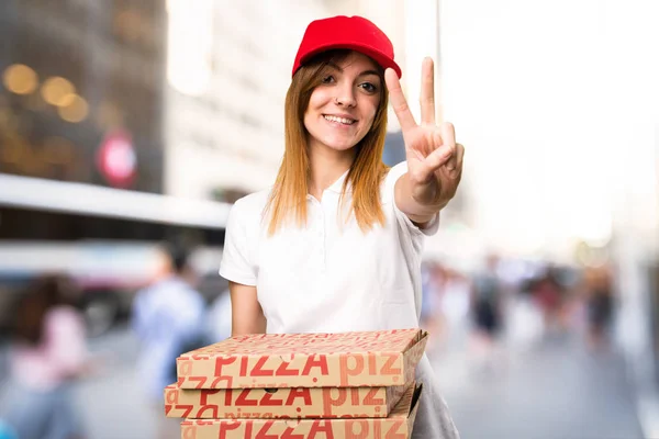 Доставка пиццы женщина рассчитывает два на несосредоточенном фоне — стоковое фото