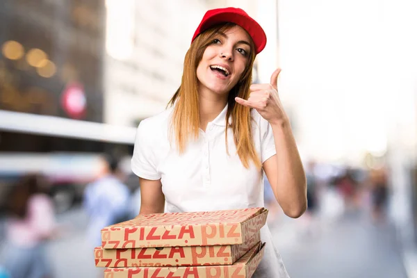 Mujer de entrega de pizza haciendo gesto telefónico en backgrou desenfocado — Foto de Stock