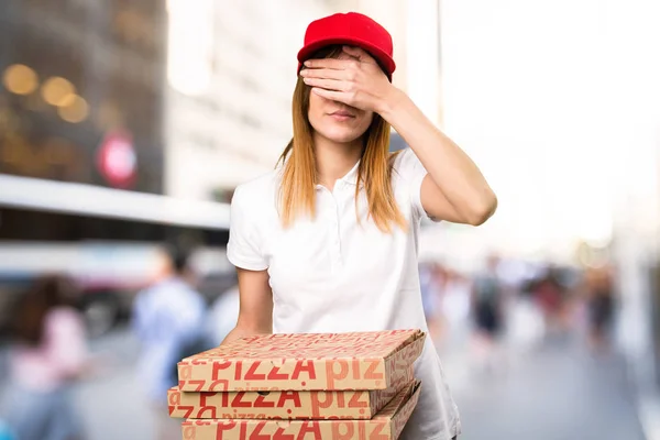 Mujer de entrega de pizza cubriendo sus ojos en un fondo desenfocado — Foto de Stock