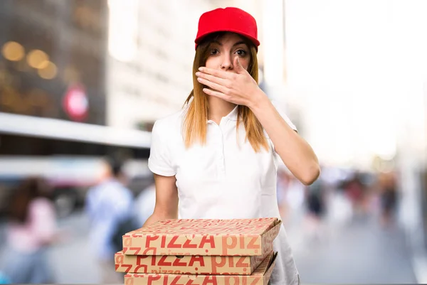Mujer de entrega de pizza cubriéndose la boca en un fondo desenfocado — Foto de Stock