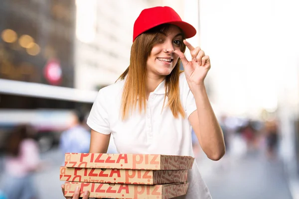 Pizza delivery woman making tiny sign  on unfocused background