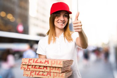 Pizza teslim kadın odaklanmamış arka plan üzerinde başparmak ile