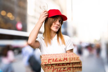 Bir ampul odaklanmamış arka planda tutan pizza teslim kadın