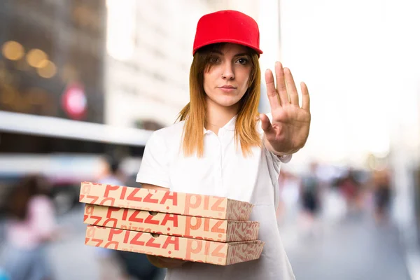 Доставка пиццы женщина делает знак остановки на несосредоточенном фоне — стоковое фото