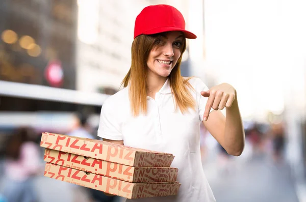 Разносчица пиццы указывает на неориентированный фон — стоковое фото