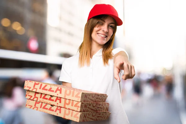 Pizza donna consegna indicando la parte anteriore sul backgro sfocato — Foto Stock