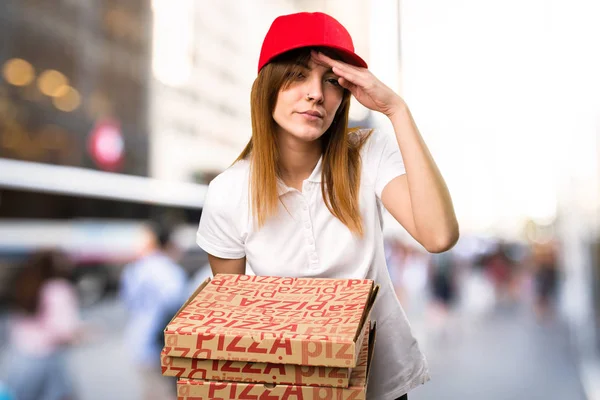 Pizza entrega mujer mostrando algo sobre fondo desenfocado — Foto de Stock