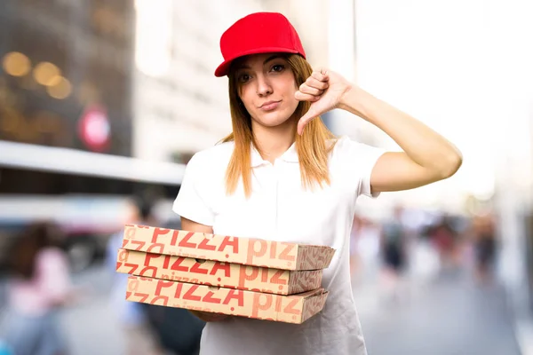 Mujer de entrega de pizza haciendo mala señal en el fondo desenfocado — Foto de Stock