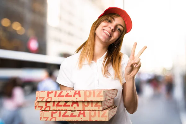 Доставка пиццы женщина делает победный жест на несосредоточенном backgr — стоковое фото