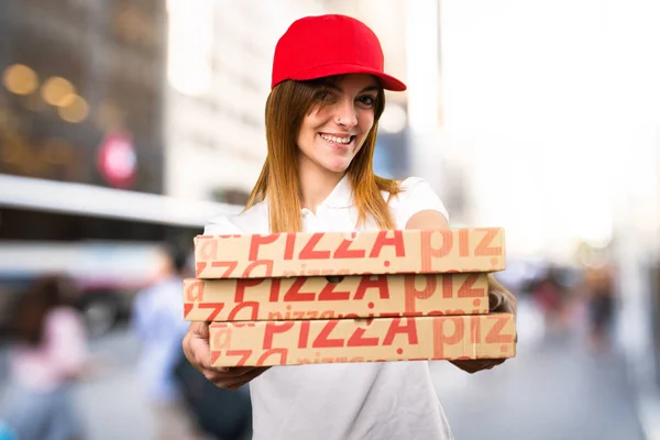 Счастливая доставщица пиццы на нефокусированном фоне — стоковое фото