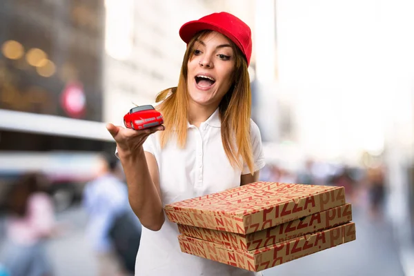 Pizza consegna donna tenendo piccola auto su sfondo sfocato — Foto Stock