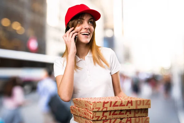 Pizza delivery woman talking to mobile  on unfocused background