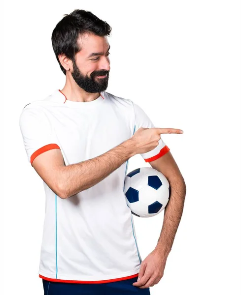 Футболіст тримає футбольний м'яч, вказуючи на бічний — стокове фото