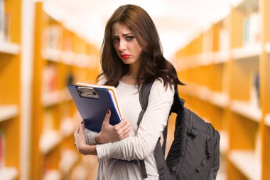 Üzgün öğrenci kadın bir Kitaplığı'nda