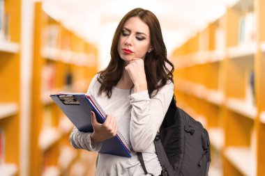 Bir kitaplıkta düşünme öğrenci kadın