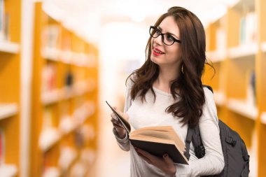 Mutlu öğrenci kadın bir Kitaplığı'nda