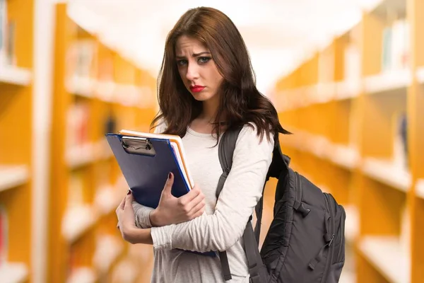 Mujer estudiante triste en una biblioteca —  Fotos de Stock