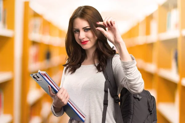 Student vrouw klein teken in een bibliotheek maken — Stockfoto