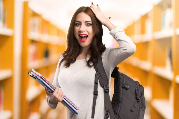 Student vrouw maken verrassing gebaar in een bibliotheek — Stockfoto