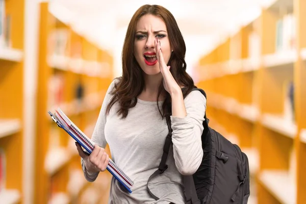 Studerande kvinna skriker i ett bibliotek — Stockfoto