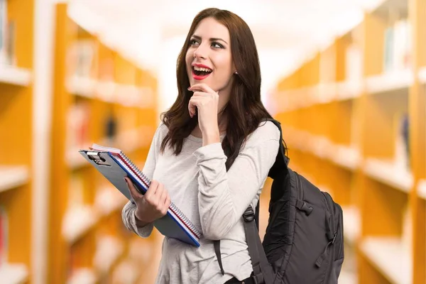 Studerande kvinna tänkande i ett bibliotek — Stockfoto