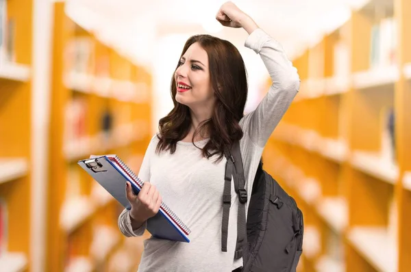 Счастливая студентка в библиотеке — стоковое фото