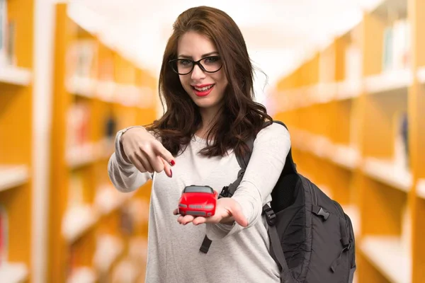 Студентка, держащая маленькую машину в библиотеке — стоковое фото
