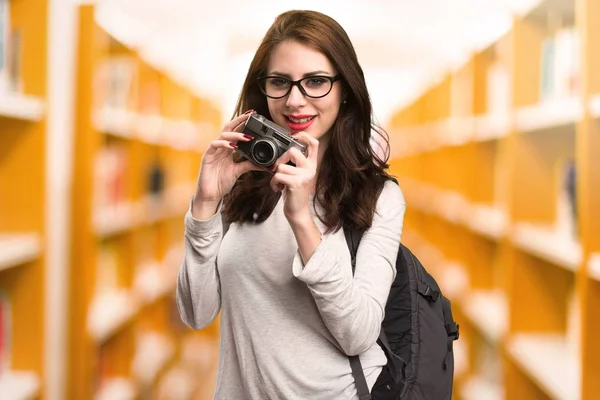 Студентська жінка тримає камеру в бібліотеці — стокове фото
