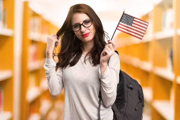 Estudiante sosteniendo una bandera americana en una biblioteca —  Fotos de Stock