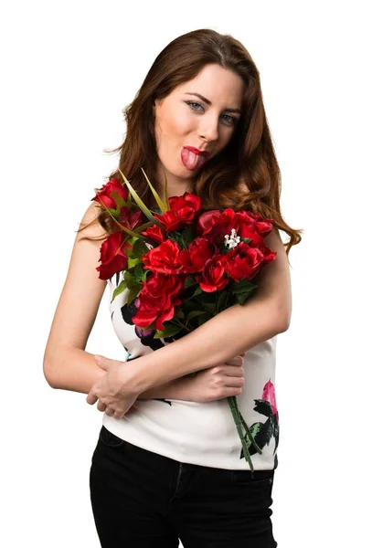 Menina bonita segurando flores tirando a língua — Fotografia de Stock