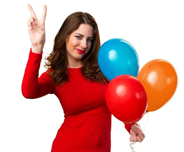Красивая молодая девушка держит воздушные шары и делает победный жест — стоковое фото