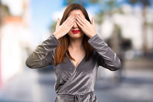 Vacker ung flicka som täcker hennes ögon på ofokuserat bakgrund — Stockfoto