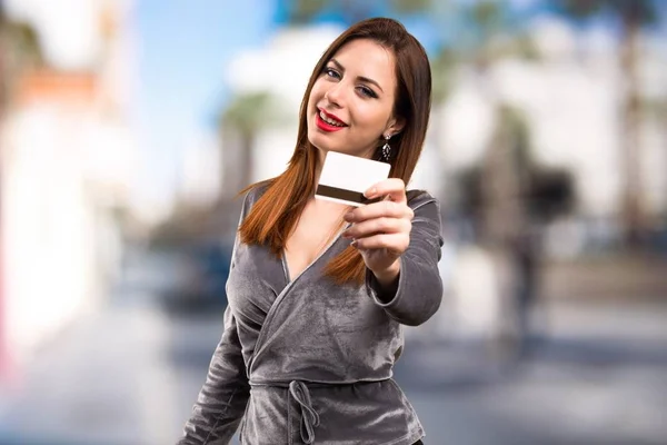 Beautiful young girl holding a credit card on unfocused background