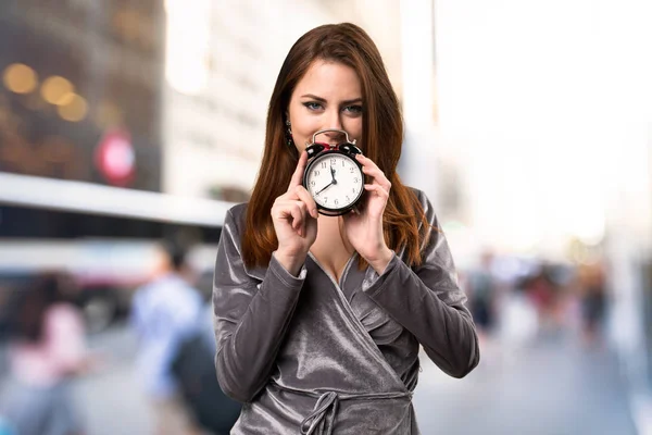 Schönes junges Mädchen mit Vintage-Uhr auf unkonzentriertem Hintergrund — Stockfoto