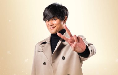 Asya yakışıklı adam yapma zafer jest koyu sarı zemin üzerine