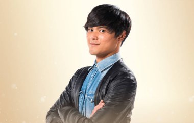 Asya yakışıklı adam kollarını ile koyu sarı arka plan üzerinde çarpı işareti