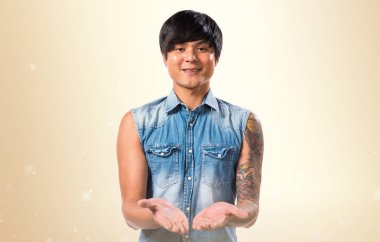 Bir şey Koyu sarı arka plan üzerinde tutan Asya yakışıklı adam