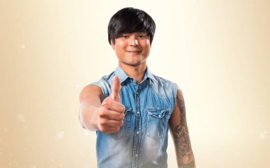 Koyu sarı zemin üzerine başparmak ile Asya yakışıklı adam