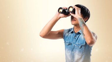 Koyu sarı arka plan üzerinde dürbün ile Asya yakışıklı adam