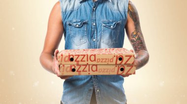 Pizza kutuları koyu sarı zemin üzerine tutarak Asya yakışıklı adam