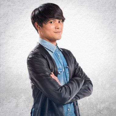 Asya yakışıklı adam kollarını ile dokulu arka plan üzerinde çarpı işareti