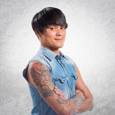 Asya yakışıklı adam kollarını ile dokulu arka plan üzerinde çarpı işareti