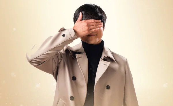 Asiatische schöner Mann bedeckt seine Augen auf ocker Hintergrund — Stockfoto