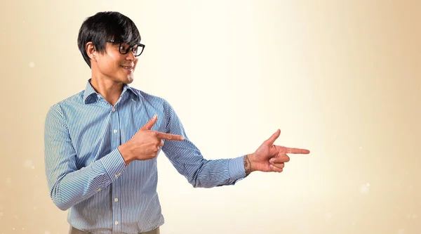 Asiatiska stilig man med glasögon pekar på lateralen på ockra — Stockfoto