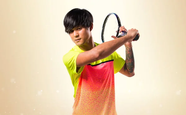 Azjatycka tenis gracz człowieka na tle ochry — Zdjęcie stockowe
